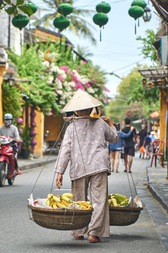 Unrecognizable traditional banana fruit vendor from behind in Hoi An, Vietnam.