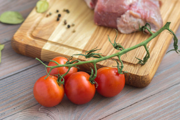 Fresh meat on the wooden table with spices and tomatoes