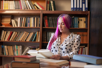 girl reading a book in the library is preparing for exams
