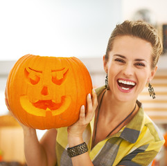 happy housewife showing a big orange pumpkin Jack-O-Lantern