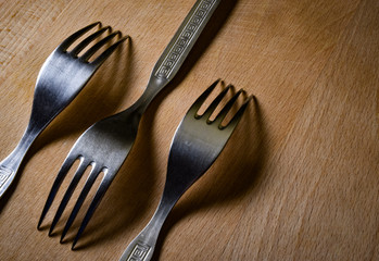 Three forks on a wooden board in the shade