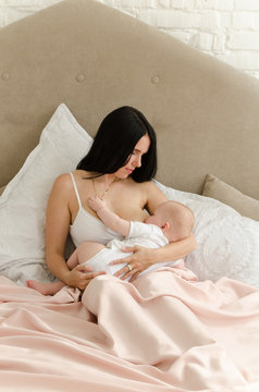 Breastfeeding. Young mother nursing baby. Family at home