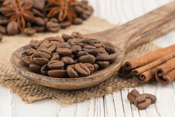 Coffee beans in a wooden spoon on old wooden table.