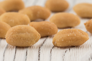 Salted peanuts on white old wooden table.