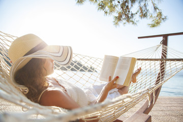 Woman in a hammock with book on holiday