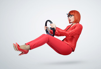 Young woman in red driver car with a steering wheel, auto concept