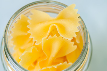 Raw pasta in a glass jar. White background.