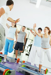 Group of people doing stretching exercise with instructor.