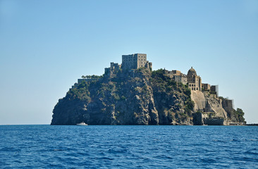 Aragonese castle on a cliff on the background of blue sky and blue sea