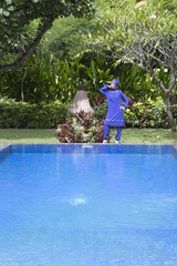 attractive woman in a Muslim swimwear burkini stand on a pool side in a tropical garden