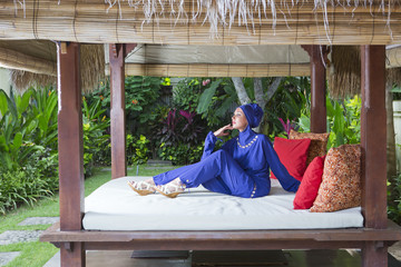 Obraz na płótnie Canvas attractive woman in a Muslim swimwear burkini in gazebo for rest in a garden