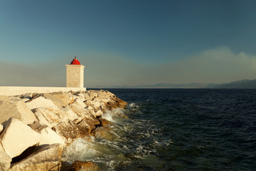 Fototapeta na wymiar Lighthouse in the harbor of a of a small town on a stormy day - Croatia, island Brac