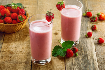 Fresh strawberry milkshake on a wooden table. Healthy fruit smoothie drink.