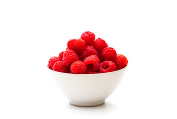 A white bowlful of juicy, ripe red raspberries on an isolated white background with copy space.
