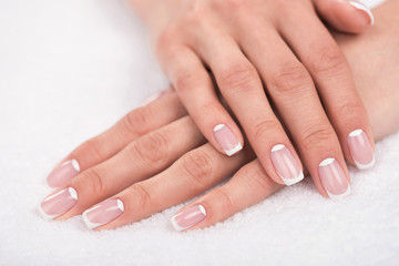 close-up view of beautiful female hands with french manicure on white