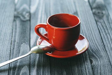 A cup for espresso is a classical form of red color on a wooden table