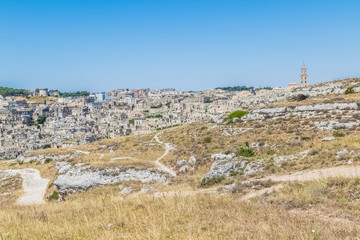 Fototapeta na wymiar panoramic view of typical stones (Sassi di Matera) and church of Matera UNESCO European Capital of Culture 2019 under blue sky. Basilicata