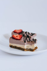 A useful raw dessert made of nuts and dried fruits, from currant mousse, adorned with strawberries