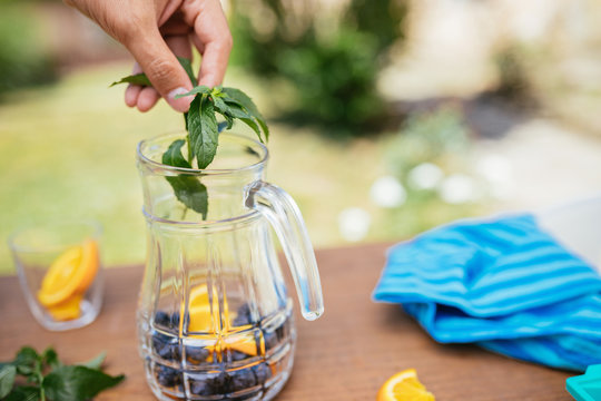 Placing Mint In The Glass Bottle With Blueberries And Orange