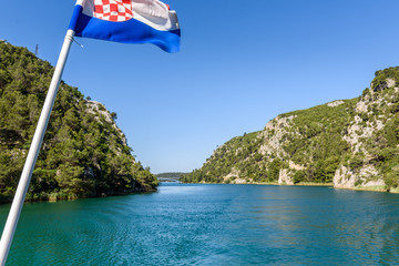 Naklejka premium Krka river valley and Croatian flag on the foreground, Krka National Park in Croatia.