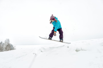 Fototapeta na wymiar Young woman on the snowboard jumping