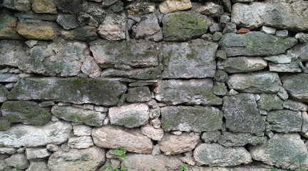 Old masonry of irregularly shaped green mossy stones. Aged stonework_2