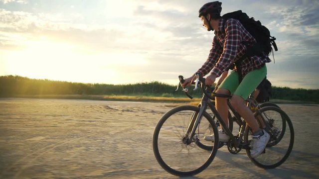 Cyclists rides together helmets sand seaside sundown slow motion rapid 