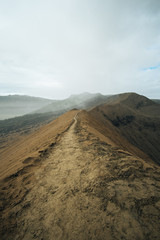 a path on a Bromo volcano rim in Indonesia. Volcano ashes are full on the path after the eruption. The road look long forward to nowhere. 