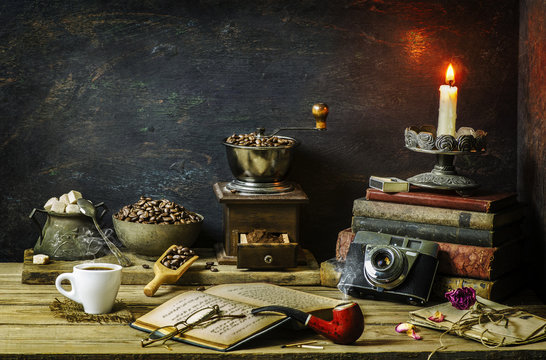Fototapeta Classic still life  with old coffee grinder placed with roasted coffee beans,sugar,vintage books,old camera and pipe on rustic wooden background