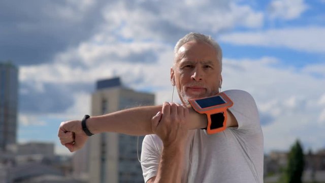 Confident senior man stratching his arms outdoors