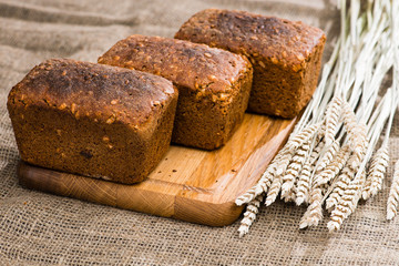 homemade rustic rye breads with seeds on a wooden cutting board, near the wheat. Selective focus, rustic style
