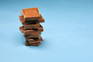 stack of chocolate pieces, close up shot with selected focus on a bright rustic wooden background