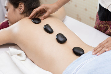 Obraz na płótnie Canvas Beautiful Young Woman getting a hot stone on back at spa salon, health and healing concept.