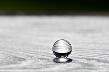 Water gel ball on wood silver texture. Hydrogel with beautiful transfusion of light.