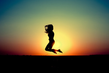 teen girl jumping at sunset. silhouette photo