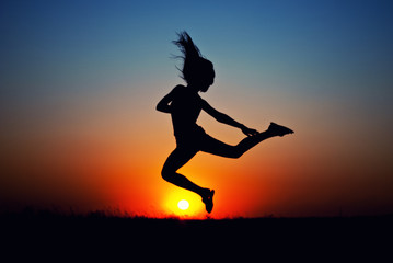 Fototapeta na wymiar teen girl jumping at sunset. silhouette photo