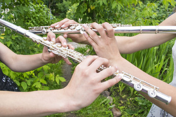 Two girls playing the flute in the garden. © Tatiana