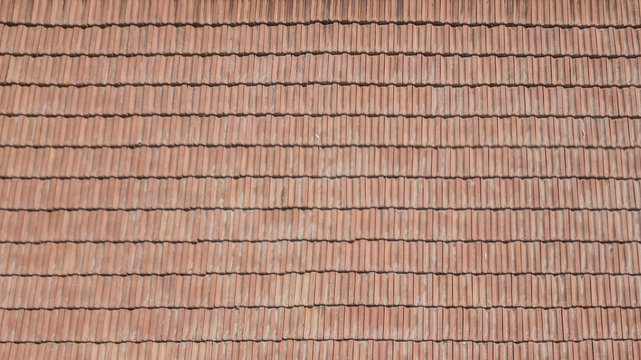 Vista aerea di un tetto formato da tegole rosse ordinate ma anche rovinate dal tempo.