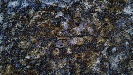 Rough yellow stone texture with black inclusions. Raw rocky mineral background