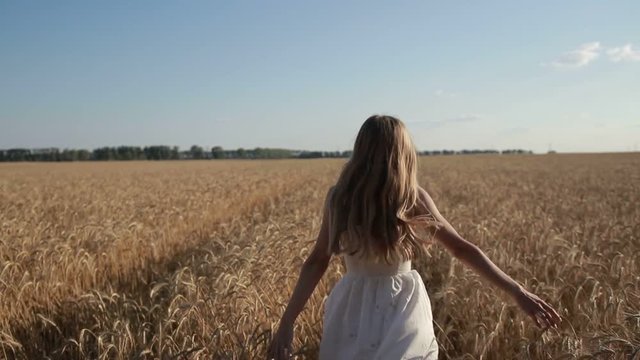 Carefree woman running through golden wheat field
