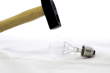 Bombilla a punto de ser rota con un martillo como concepto de Fragilidad 