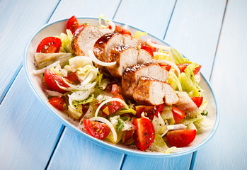 Grilled chicken fillet and vegetables on wooden background