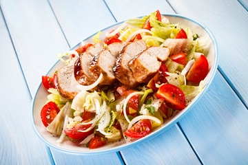Grilled chicken fillet and vegetables on wooden background