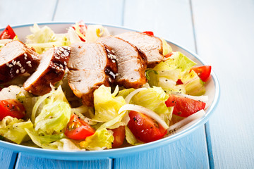 Grilled chicken fillet and vegetables on wooden background