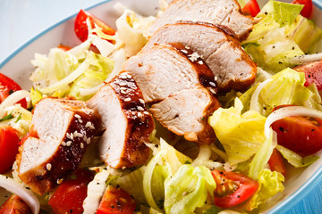 Grilled chicken fillet and vegetables on wooden background