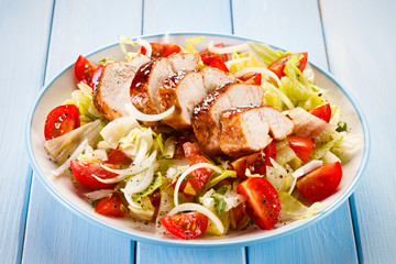 Grilled chicken fillet and vegetables on wooden background