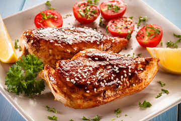 Roast chicken fillet and vegetables on wooden background