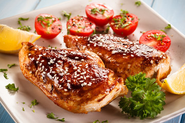 Roast chicken fillet and vegetables on wooden background