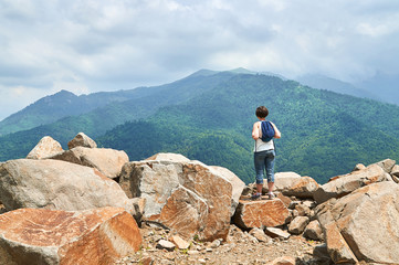 Woman with backpack standing on the rock top and enjoying beautiful view 