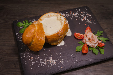 Fresh pea soup in a Bread Bowl, on a wooden board with salt and papper